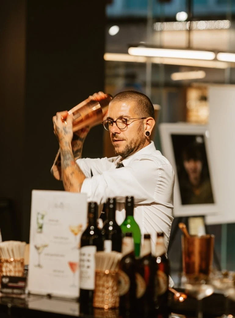 Expert bartender pouring a freshly mixed cocktail into a glass.