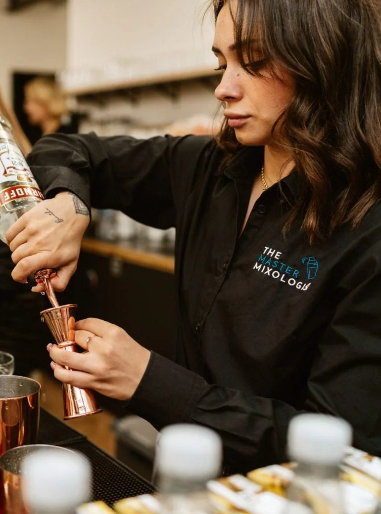 Cocktail bartender serving a beautifully crafted drink to a guest."